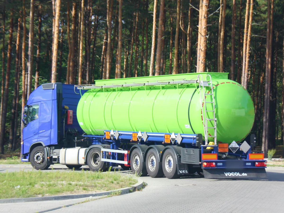 Chemical tank semi-trailer with orange ADR plates 80/3264 and class 8 labels on a forest road