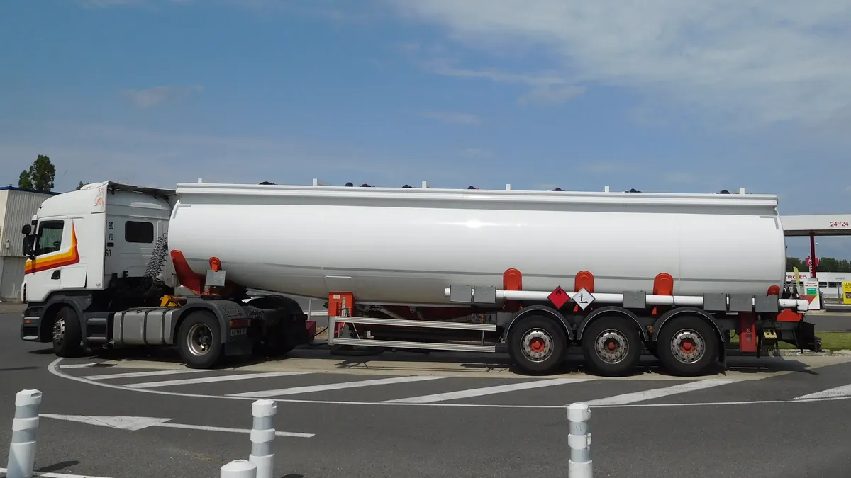 Tank semi-trailer for bulk liquids behind a Scania tractor at a filling station forecourt