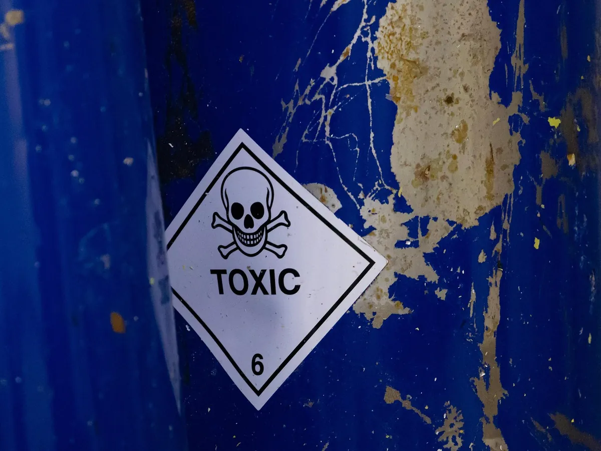Gefahrzettel der Klasse 6.1 mit Totenkopf und dem Wort TOXIC auf einem blauen Fass