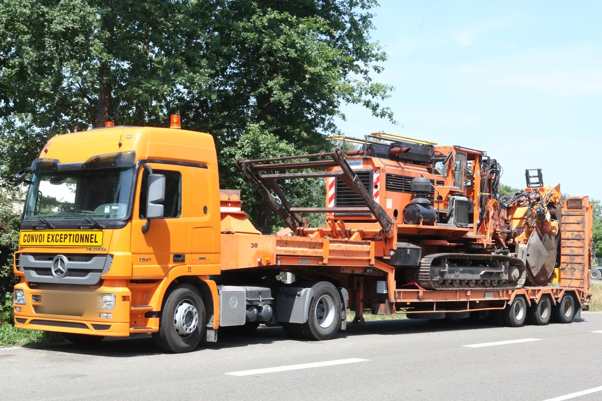Tieflader mit einer Kettenmaschine als Schwertransport, die Zugmaschine mit dem Schild Convoi exceptionnel