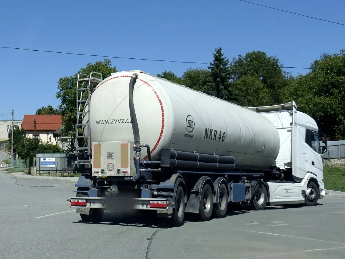DAF tractor with a silo semi-trailer on a village road in Slovakia, the equipment a silo carrier runs