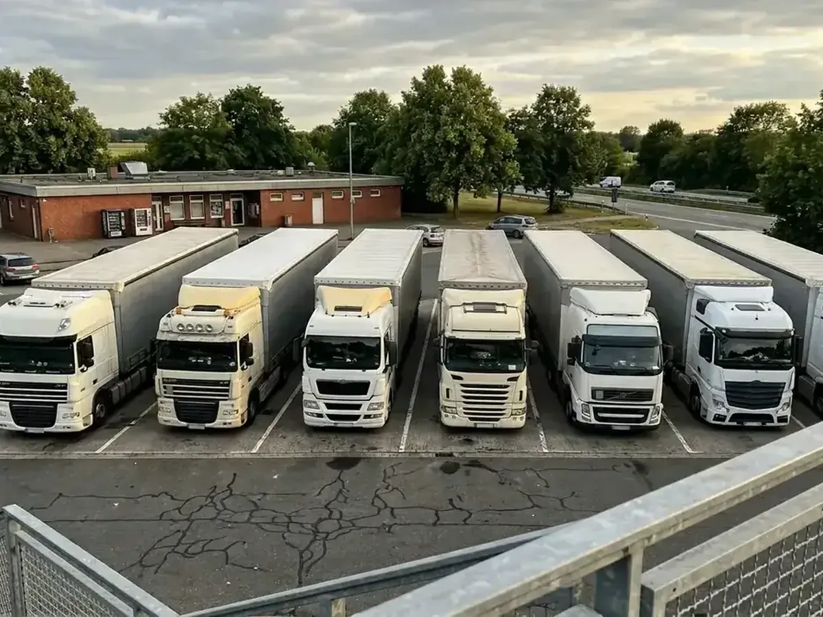 Sattelzüge in einer Reihe auf einem Lkw-Parkplatz an der Autobahn, abgestellt wie während eines Fahrverbots