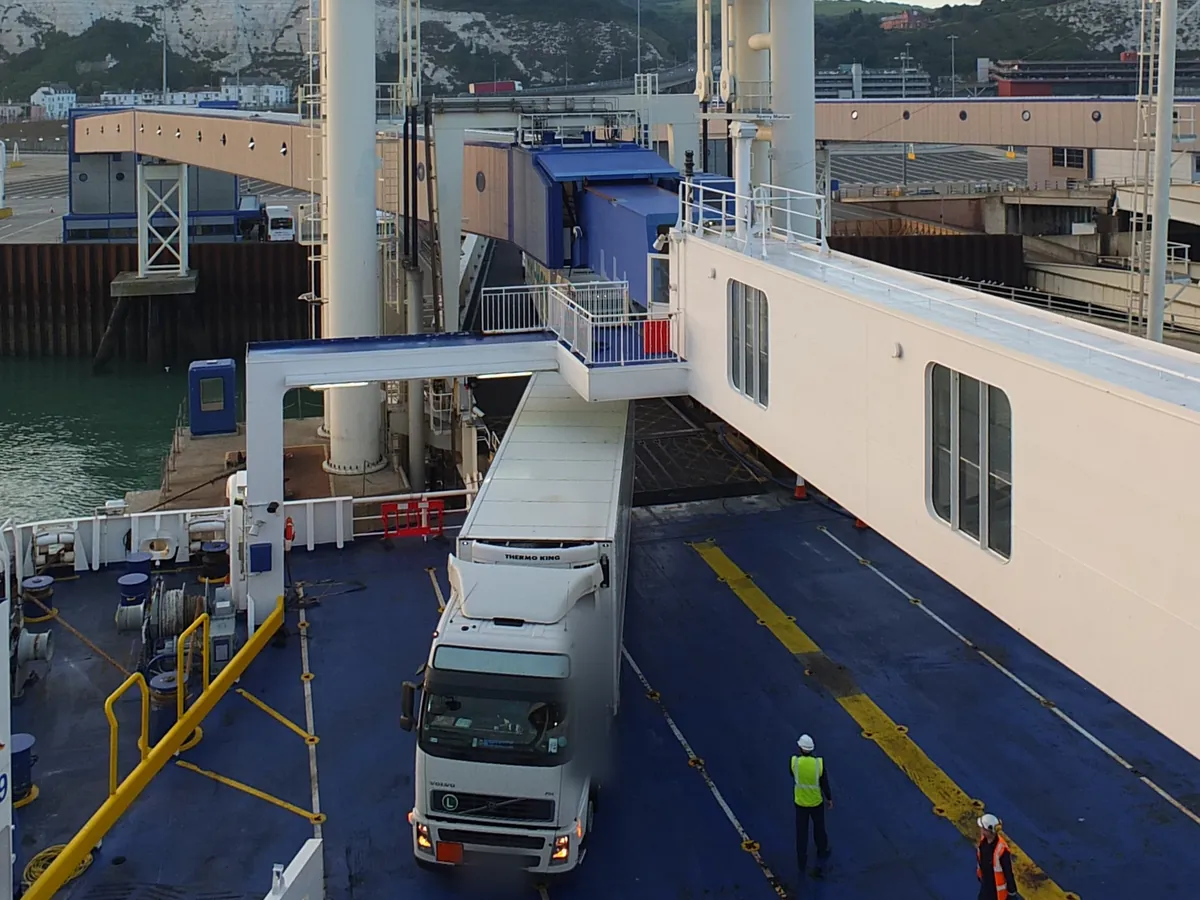 A lorry boarding a ferry at pier 9 in Dover, the white cliffs behind