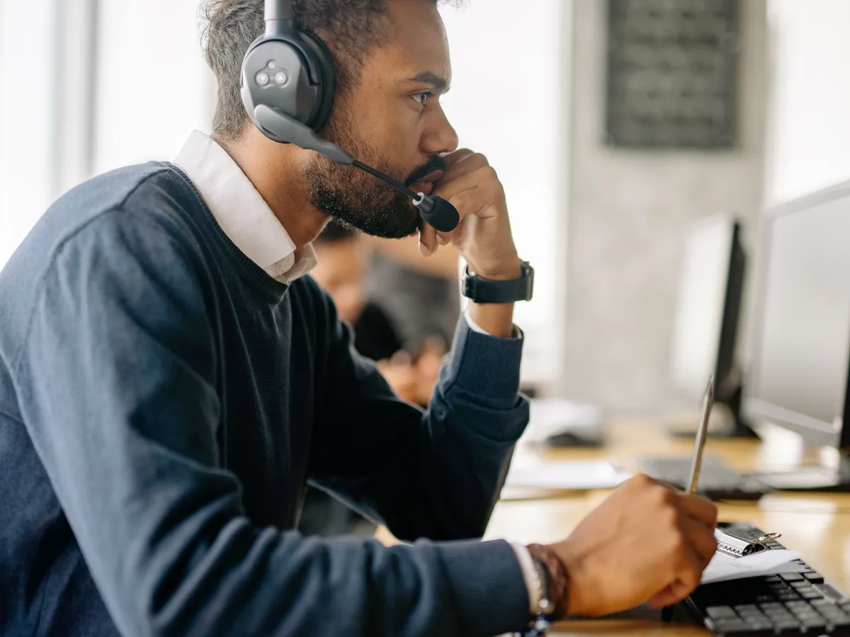 Een planner met headset aan een bureau met beeldschermen, van waaruit vervoerders worden begeleid